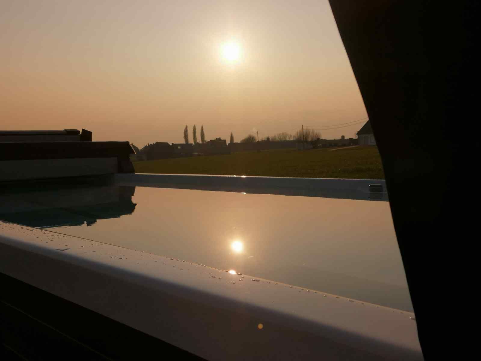 Prachtig uitzicht op de zonsondergang vanaf vakantiehuis BK025 in Zandvoorde, West-Vlaanderen met spiegeling in het water.