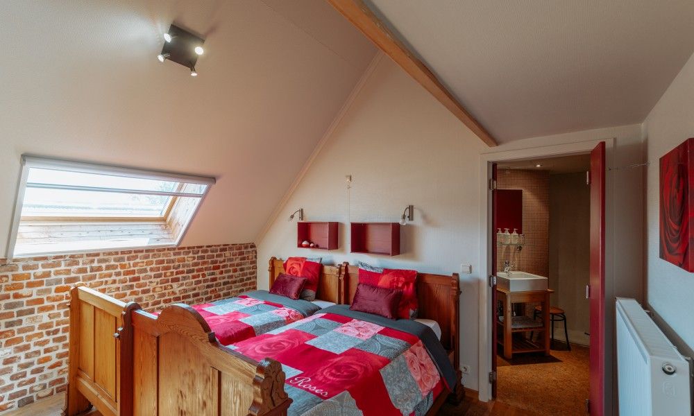 Attraktives Schlafzimmer im Ferienhaus De Bronne, Flaemische Ardennen, mit Holzakzenten und Dachfenster.