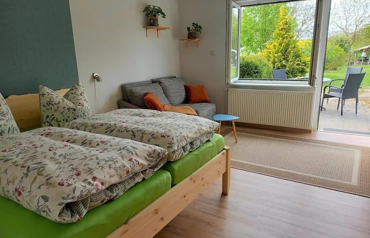 Gezellige slaapkamer in Vakantiehuis in Leinefelde-Worbis, Thuringen, met uitzicht op de groene tuin en comfortabele zitruimte.