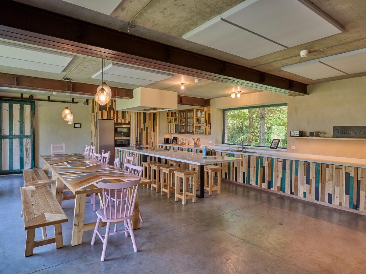 Stijlvolle keuken in vakantiehuis Lactea, Schilde, Antwerpen met houten interieur en grote ramen met uitzicht op de natuur.