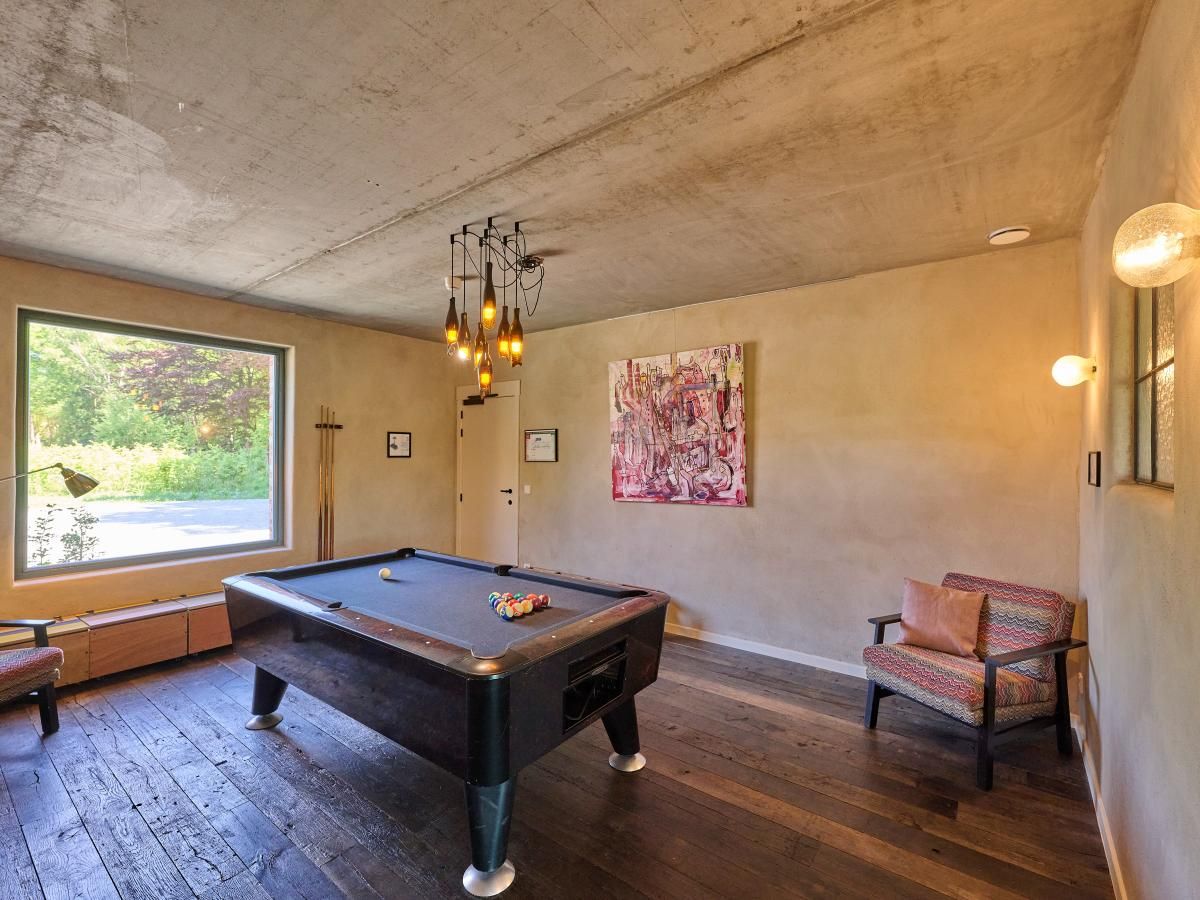 Ontspannen in de recreatieruimte van vakantiehuis Lactea in Schilde, Antwerpen, met pooltafel en kunstzinnige inrichting.