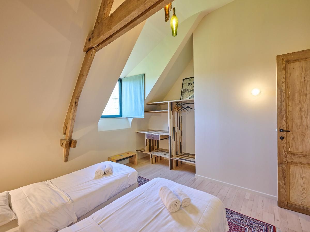 Gezellige slaapkamer in vakantiehuis Lactea, Schilde, Antwerpen met houten balken en serene inrichting voor een ontspannen verblijf.