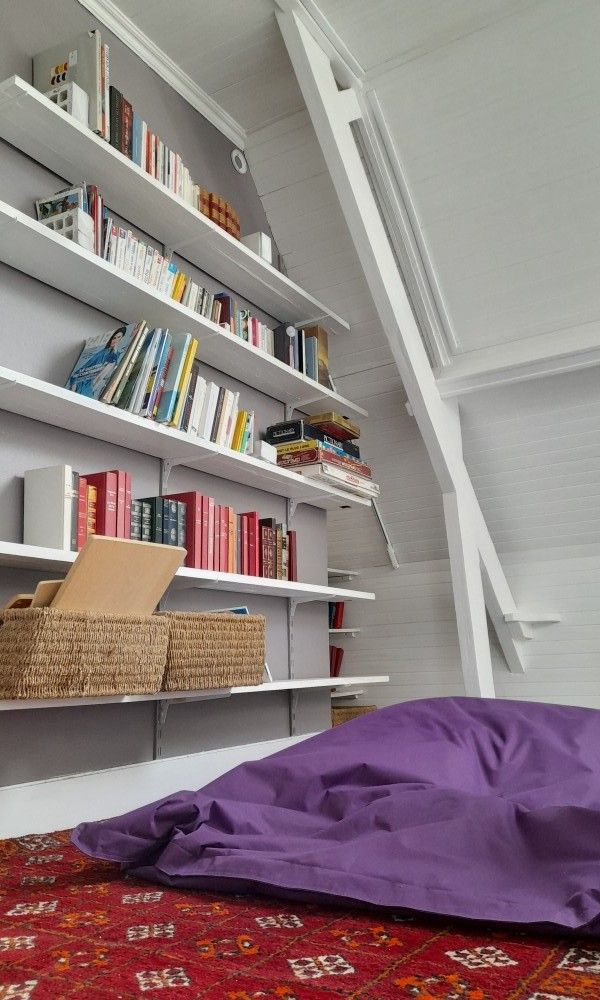 Gezellige leeshoek in Gite Troubadour, vakantiehuis in Audinghen, Frankrijk met boekenplanken en paarse zitzak.