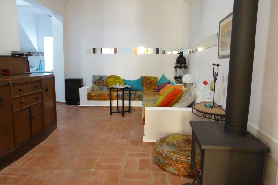 Gezellige woonkamer van vakantiehuis Casa Levante in Fuzeta, Algarve, met kleurrijke kussens en een rustieke houtkachel.