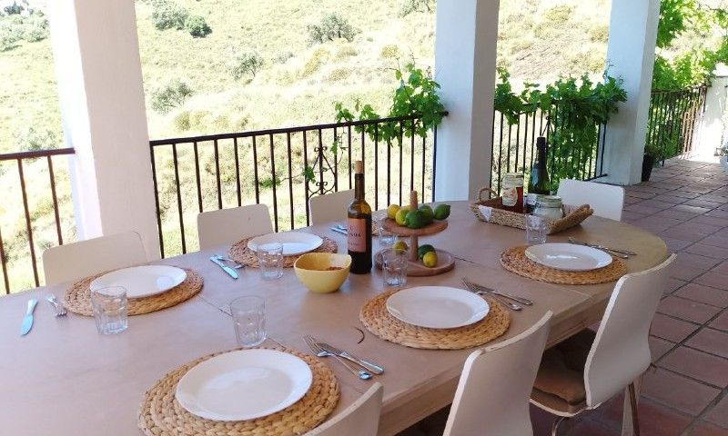 Geniet van een diner op het terras van Casa Milvan, een vakantiehuis in Competa, Andalusie, met uitzicht op de groene heuvels.