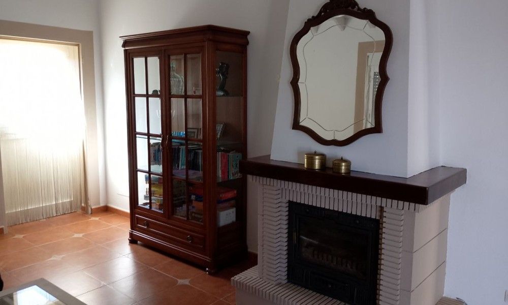 Gezellige woonkamer in Casa Milvan, vakantiehuis in Competa, Andalusie met open haard en antieke kast.