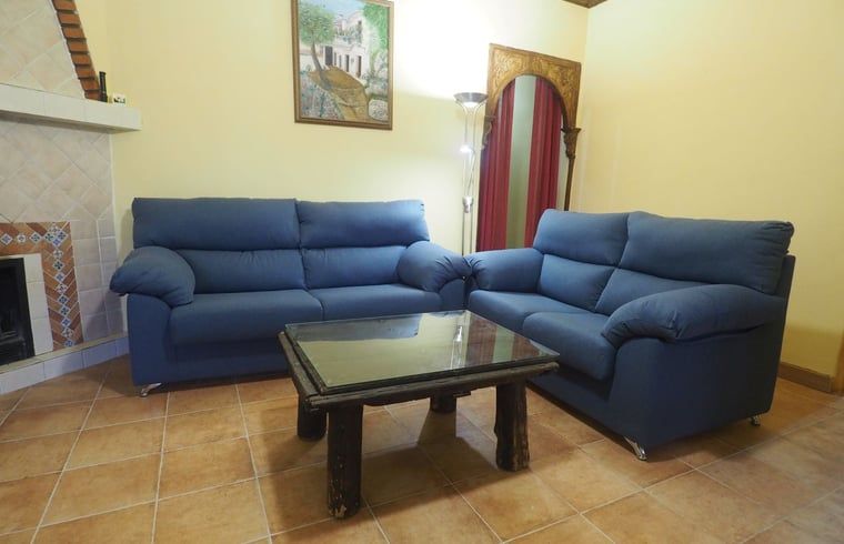 Gezellige woonkamer in Vakantiehuisje in La Taha, Pitres, Andalusie met comfortabele banken en rustieke inrichting.