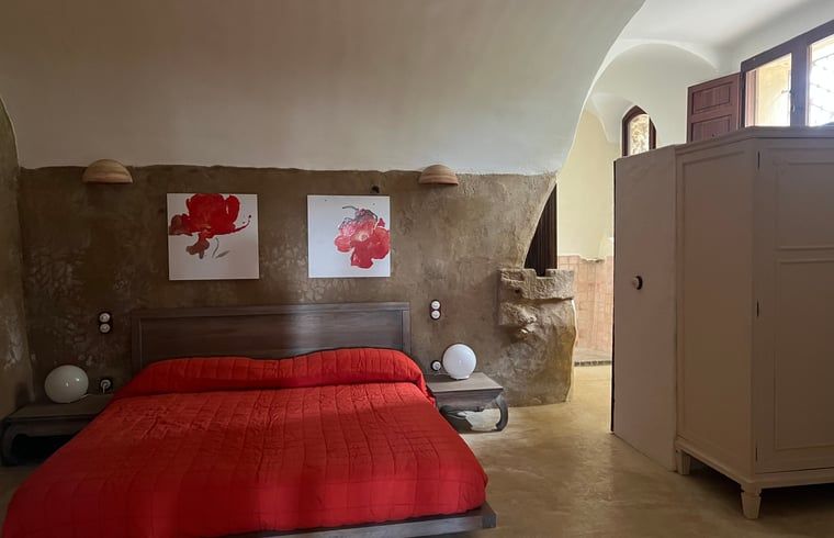 Gezellige slaapkamer in Vakantiehuisje in Navata, Costa Brava, met rustieke muren en moderne kunst.