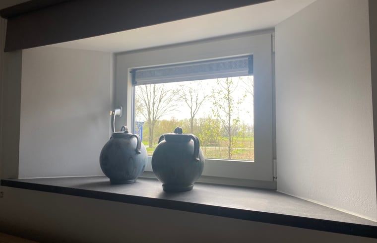 Vensterbank met decoratieve vazen in Huisje in Beers, vakantiehuis in Beers NB, met uitzicht op de tuin.