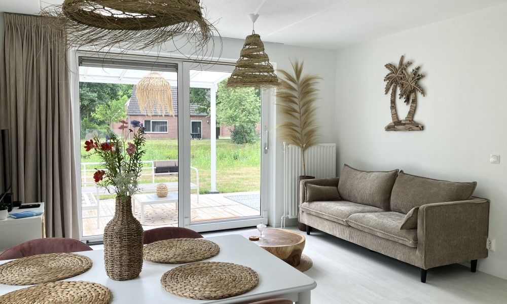 Gezellige woonkamer van Forest Escape-Luxe natuurhuis met Sauna & Jacuzzi in Hoeven, West Brabant. Geniet van het uitzicht op de groene omgeving.