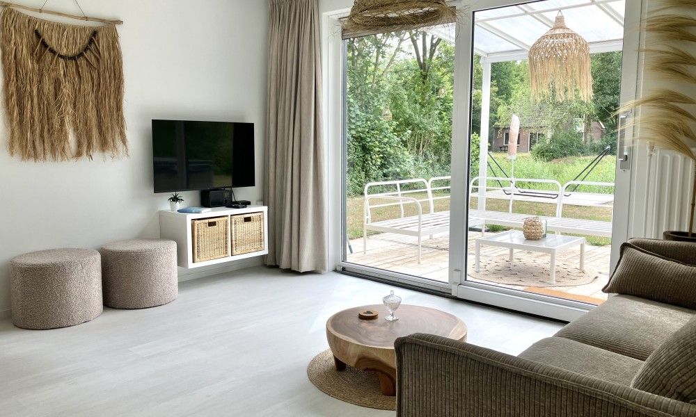 Lichte woonkamer van Forest Escape-Luxe natuurhuis met uitzicht op groene tuin in Hoeven, West Brabant. Perfect vakantiehuis voor ontspanning.