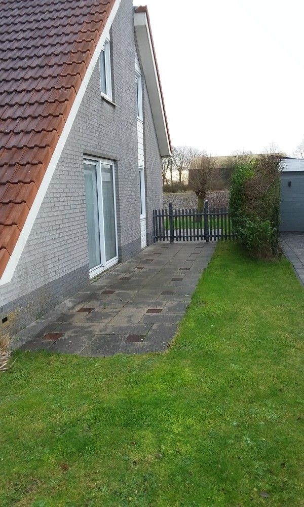 Zijaanzicht van Villa Zeerob in Scharendijke met ruim terras en tuin, ideaal voor ontspannen in Zeeland.