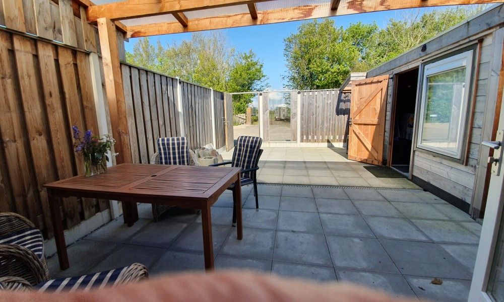 Die ueberdachte Terrasse von THE SUN IN STEE ON ZEE in Serooskerke, Walcheren, Zeeland, bietet Privatsphaere und Entspannung im Freien.