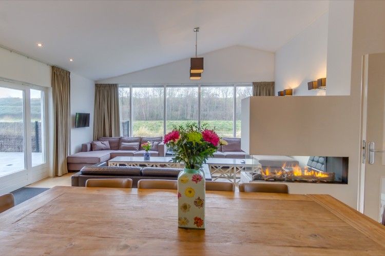 Moderne woonkamer van la Cabane in Nieuwvliet-Bad met grote ramen en uitzicht op de natuur.