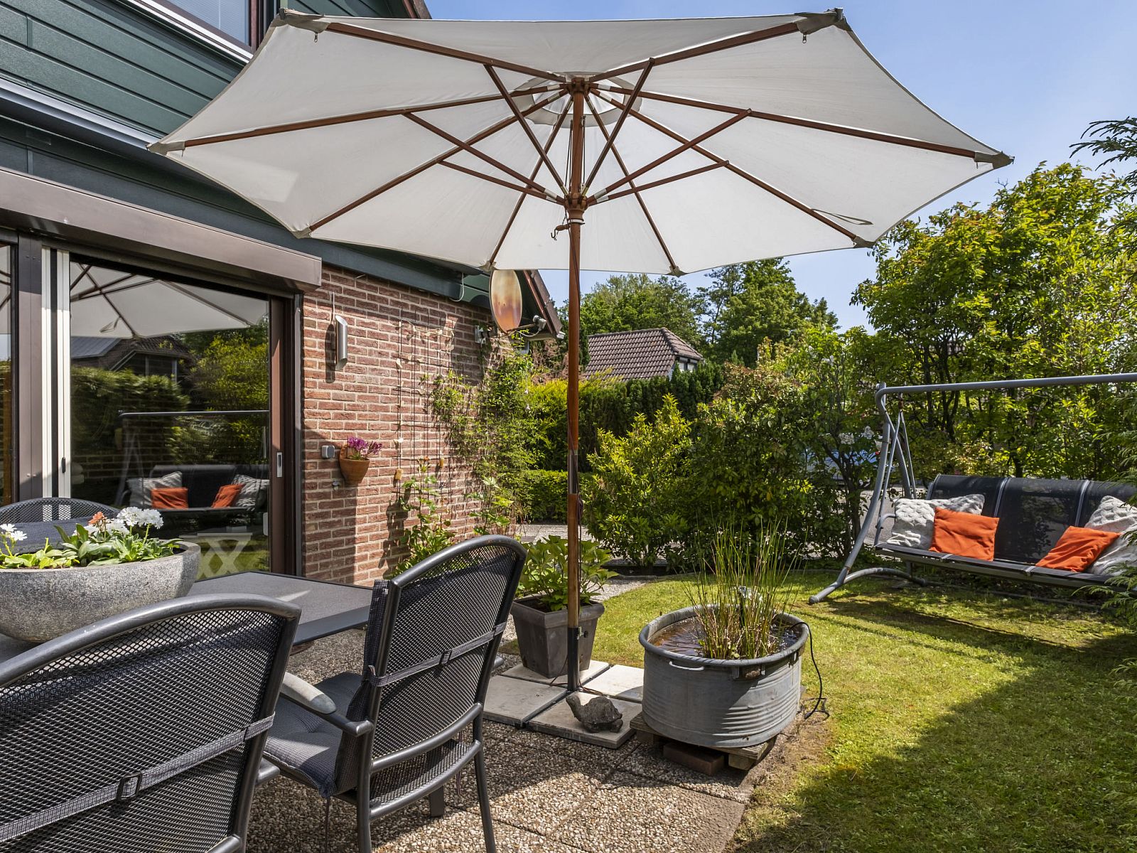 Geniet van de zonnige tuin bij Vakantiehuis Haus Anni in Hansweert, Zuid-Beveland, met comfortabele zithoek en parasol.