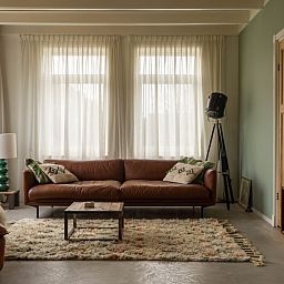 Stijlvolle woonkamer van Paal 234, een vakantiehuis in De Koog, Texel, met leren bank en vintage decor.
