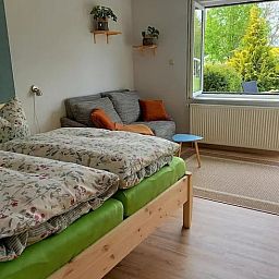 Gezellige slaapkamer in Vakantiehuis in Leinefelde-Worbis, Thuringen, met uitzicht op de groene tuin en comfortabele zitruimte.