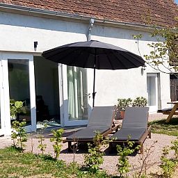 Geniet van de zon op het terras van Vakantiehuisje in Saint Bonnet Troncais, Auvergne, Frankrijk, met comfortabele ligstoelen.