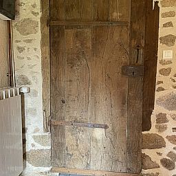 Authentieke houten deur in La Vallade vakantiehuis, Le Bourg-d'Hem, Limousin, Frankrijk, met rustieke stenen muren.