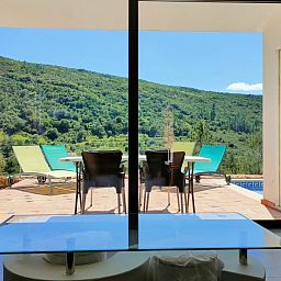 Geniet van het uitzicht op de groene heuvels vanaf de woonkamer van Casa Bananeira villa 4P + baby in Sao Bartolomeu de Messines, Algarve.
