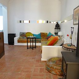 Gezellige woonkamer van vakantiehuis Casa Levante in Fuzeta, Algarve, met kleurrijke kussens en een rustieke houtkachel.