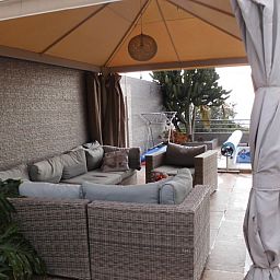 Ontspan op het gezellige terras van Casa Alex, een bed and breakfast in Adeje, Canarische Eilanden, met comfortabele zitplaatsen onder een schaduwrijke luifel.