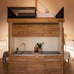 Moderne Kueche im Glamping Family Plus, einem luxurioesen Zelt-Haus in Cadaques, Costa Brava, Spanien, mit Holzverkleidung und Hochbett.