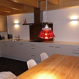 Gezellige keuken in Chalet Belpiano, Nendaz, Zwitserland met moderne inrichting en warme houten accenten.