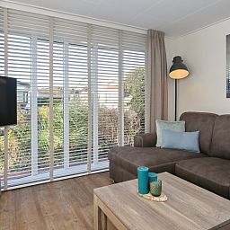 Gezellige woonkamer in De Duinpan 21 chalet met comfortabele bank in Noordwijk aan zee, Noordzeekust, Zuid-Holland.