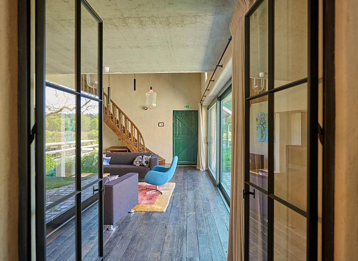 Stijlvolle woonkamer van vakantiehuis Lactea in Schilde, Antwerpen met moderne meubels en een ruimtelijk uitzicht op de tuin.