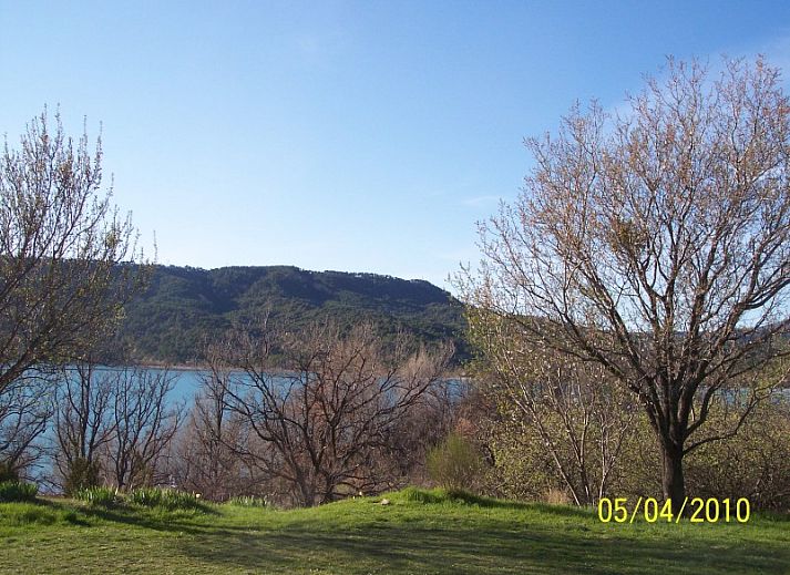 Geniet van het serene strand nabij vakantiehuis Figuier in Aiguines, Provence, omgeven door helderblauw water en groene natuur.