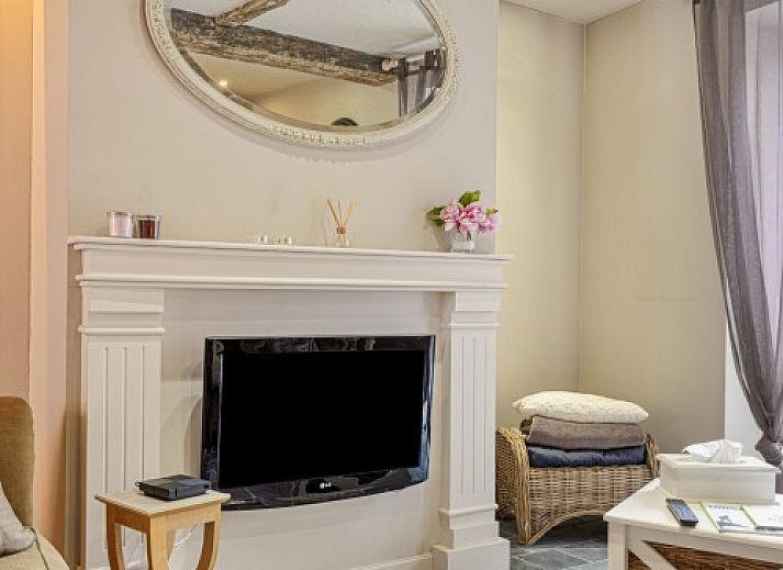 Gemuetliches Wohnzimmer des Ferienhauses Bibi Tongeren in Limburg, Belgien, mit rustikaler Steinwand und bequemer Sitzecke.