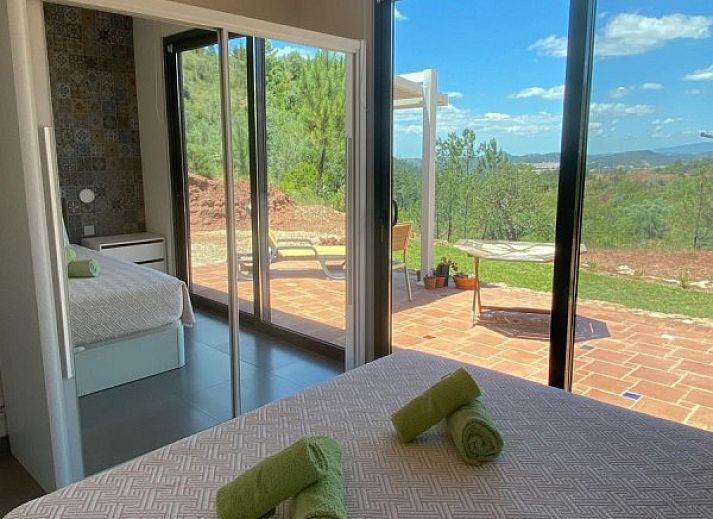 Ontspan bij het zwembad van Casa da Alfarobeira, een vakantiehuis in Sao Bartolomeu de Messines, Algarve, met uitzicht op de heuvels.