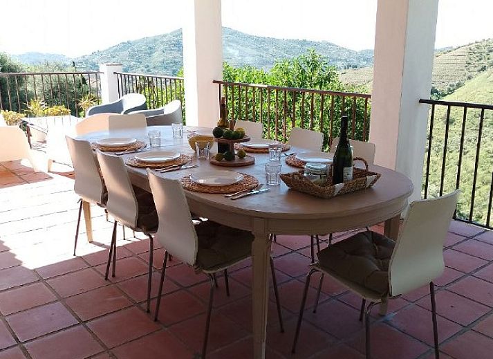 Geniet van een diner op het terras van Casa Milvan, een vakantiehuis in Competa, Andalusie, met uitzicht op de groene heuvels.