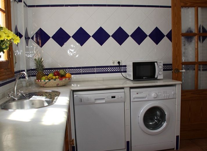 Geniet van het zonnige terras bij Apartamento Caracola in Chipiona, Costa de la Luz, Spanje, omringd door groen en een stijlvolle auto.