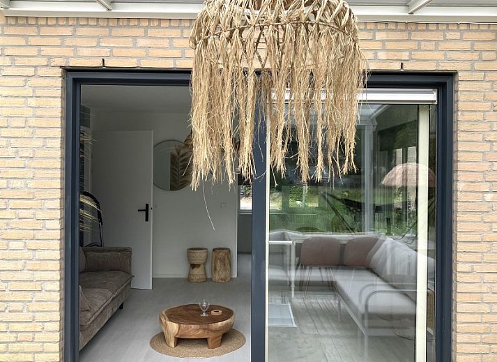 Gezellige woonkamer van Forest Escape-Luxe natuurhuis met Sauna & Jacuzzi in Hoeven, West Brabant. Geniet van het uitzicht op de groene omgeving.