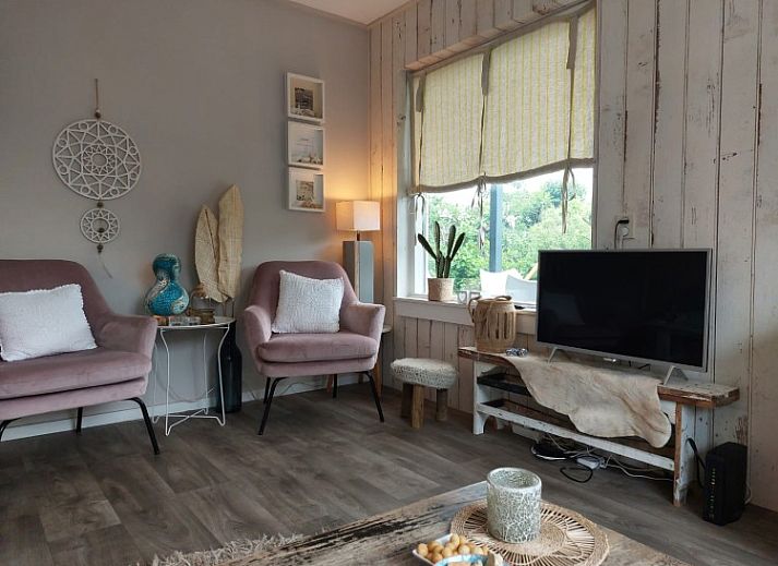 Ruim terras bij bungalow De Garnaal in Renesse, Schouwen-Duiveland met houten eettafel en groene omgeving.