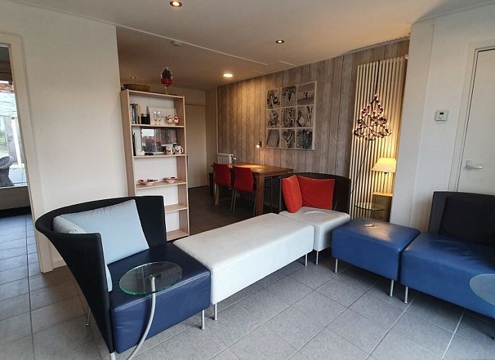 Gemuetliche Terrasse am Ferienhaus THE SUN IN STEE ON ZEE in Serooskerke, Walcheren, mit bequemen Sitzgelegenheiten und Blumen.