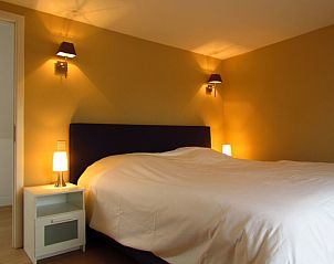 Sfeervolle slaapkamer in Hof ter Harte vakantiehuis, Ieper, West-Vlaanderen met zacht beddengoed en warme lampen.