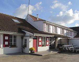 Gezellige zithoek in Hof ter Harte vakantiehuis, Ieper, West-Vlaanderen met rotan stoel en decoratieve elementen.