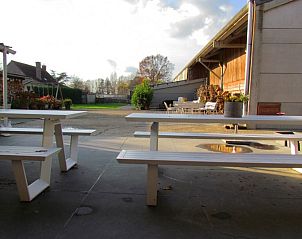 Uitzicht op binnenplaats van Hof ter Harte vakantiehuis, Ieper, West-Vlaanderen met picknicktafels en blauwe lucht.