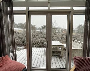 Winteruitzicht vanuit Spreeuw88 chalet, Den Hoorn, Texel met besneeuwd terras op de Waddeneilanden.