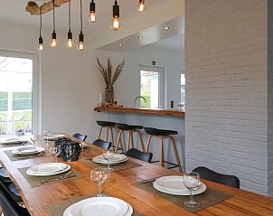 Villa de Strandjutter in Nieuwpoort-Bad, West-Vlaanderen, biedt een eetruimte met uitzicht op de tuin en moderne inrichting.