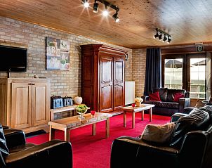 Gezellige woonkamer in De Finesse vakantiewoning in Koekelare-Bovekerke, West-Vlaanderen met rode accenten.