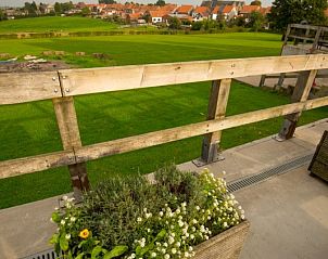 Uitzicht vanaf De Bosgeus vakantiehuis in Nieuwkerke, West-Vlaanderen met groene velden en kerktoren.