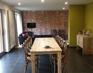 Stijlvolle woonkamer in de Kortweunste vakantiehuis, Merkem, met bakstenen muur en comfortabele zitplaatsen.