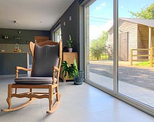 Zonnige zithoek met schommelstoel in Vakantiewoning Huis Huwyn, Lichtervelde, biedt een prachtig uitzicht op de omgeving.