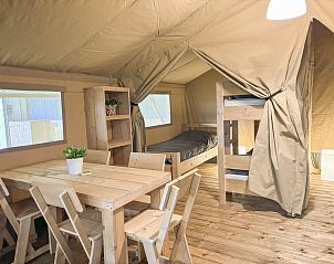 Cozy interior of a safari tent in Aars, North Jutland, Denmark, featuring wooden furnishings and bunk beds.