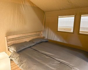 Cozy bedroom in a safari tent, a glamping lodge in Aars, North Jutland, Denmark, featuring comfortable furnishings.
