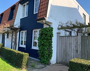 Charmante gevel van St Kwintens vakantiehuis in Knokke-Heist, Belgi met klimplanten en houten hek.